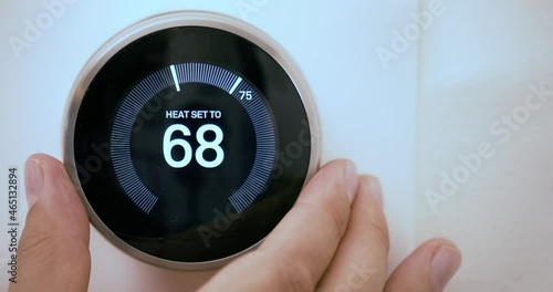 A person increasing the temperature on a Smart Thermostat on fahrenheit scale photo