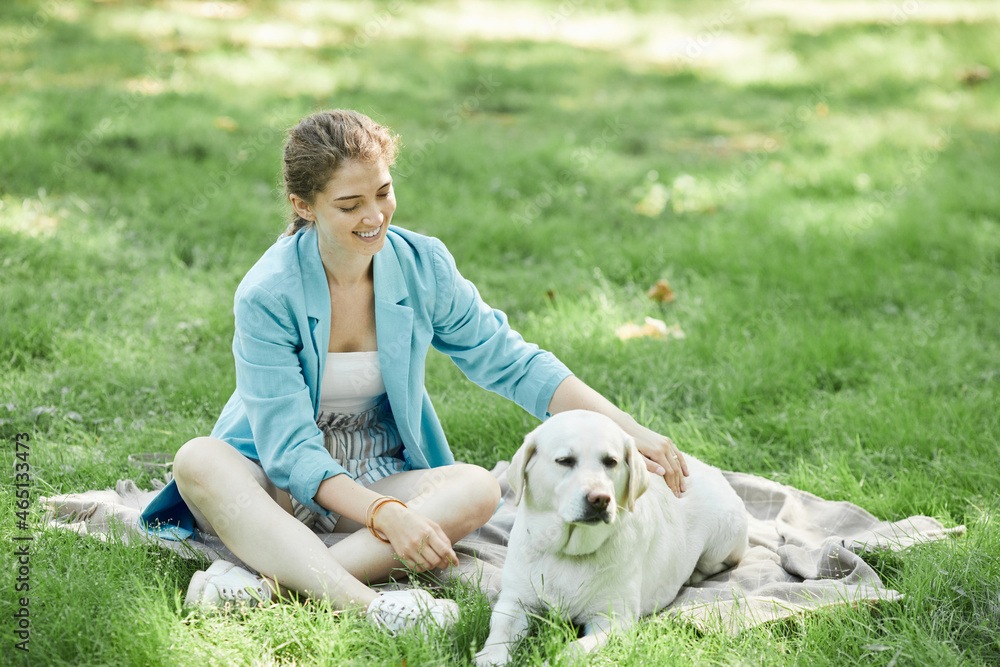 Full length portrait of smiling young woman playing with dog outdoors while enjoying walk together in park, copy space Full length portrait of smiling young woman playing with dog outdoors while enjoying walk together in park, copy space