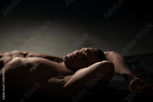 Sexy naked muscular man with sixpack abs lying in bed. Attractive young gay. Wellness, wellbeing concept. photo