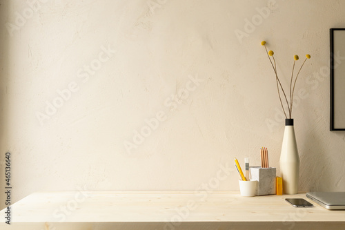 Stylish desk with dry plant, laptop, mobile and natural textured wall copy space. Minimal workspace desk of designer.	