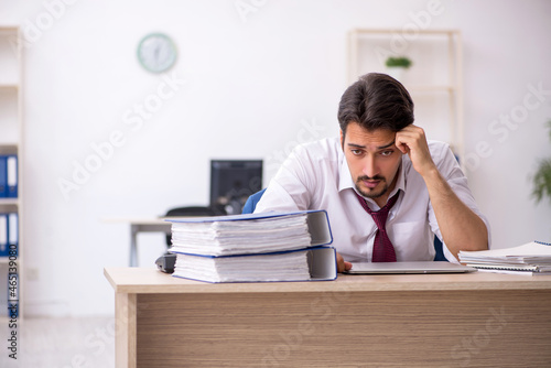 Young male employee unhappy with excessive work in the office