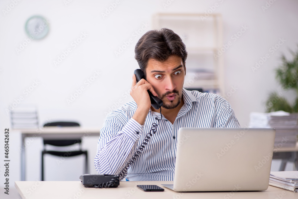 Young male employee and too much work in the office Young male employee and too much work in the office