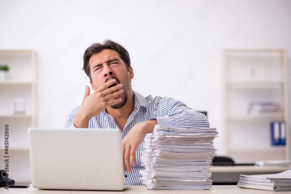 Young male employee and too much work in the office Young male employee and too much work in the office