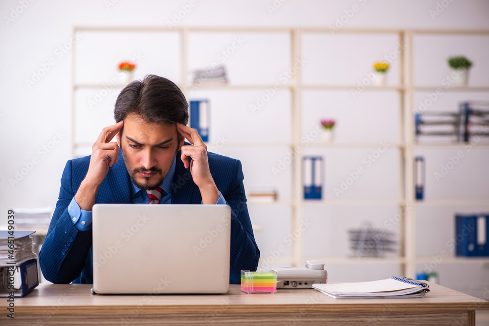 Young male employee sitting at workplace Young male employee sitting at workplace