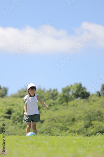 芝の上でサッカーをする女子小学生 (6歳)