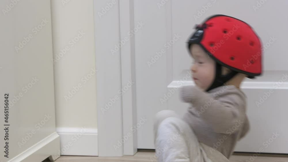 Baby boy wearing soft safety helmet falls backwards and hits his head on the floor, child crying lying on his back, head protector helps reduce impact of fall. High quality 4k footage Baby boy wearing soft safety helmet falls backwards and hits his head on the floor, child crying lying on his back, head protector helps reduce impact of fall. High quality 4k footage