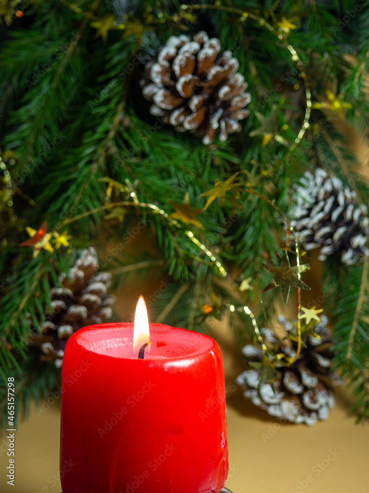 New Year's decorations. Pine cone, candle and  fir branches on a beige background.