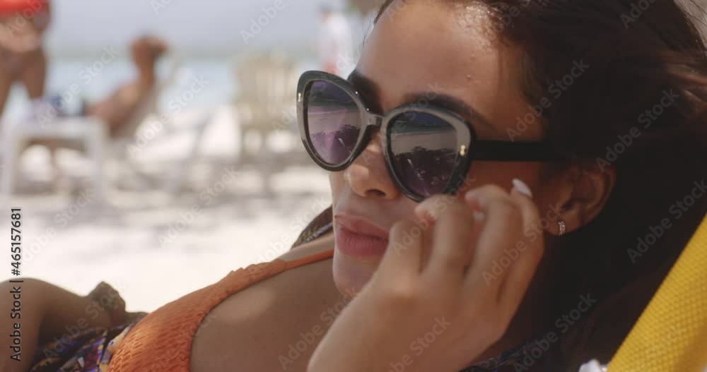 Latin Girl on Beach Resort on Bright Sunny Day Lowers Sunglasses to Peer Out at View, Close up Latin Girl on Beach Resort on Bright Sunny Day Lowers Sunglasses to Peer Out at View, Close up