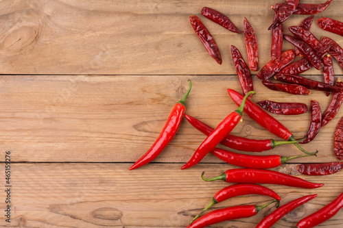 Fresh chili and dried chili, placed on the wooden floor, top view with copy space.