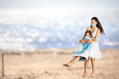 Mother, child in masks have fun on sea beach. coronavirus COVID 19.
