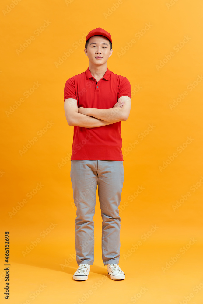 Deliveryman with arms crossed in studio. looking at camera. Full length portrait. isolated gray background