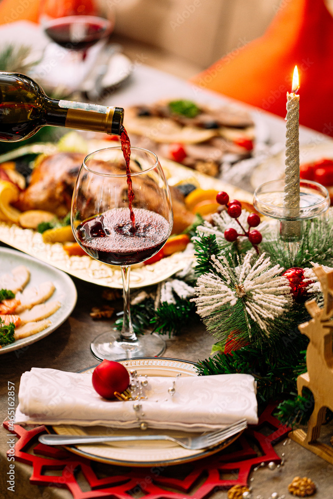 Pouring red wine in a glass on new year festive served table