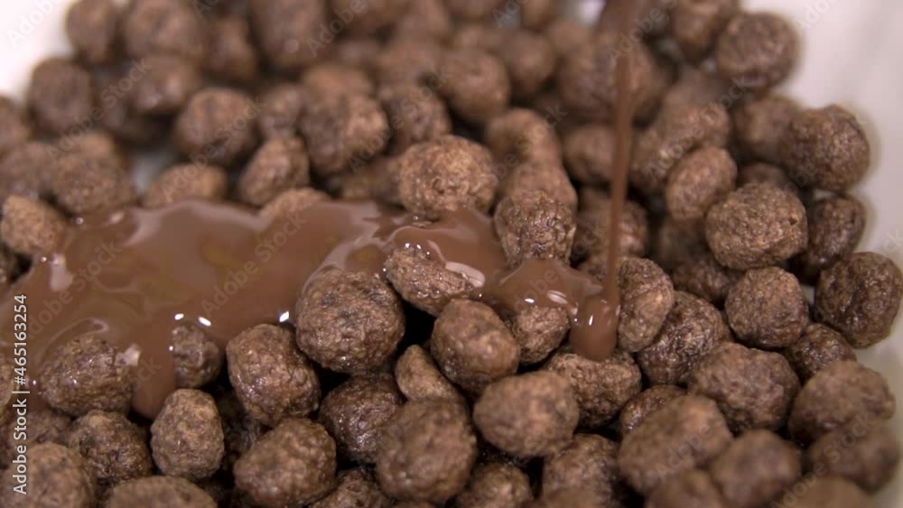 Chocolate sauce falling on choco ball cereal in a bowl - Slow motion Chocolate sauce falling on choco ball cereal in a bowl - Slow motion