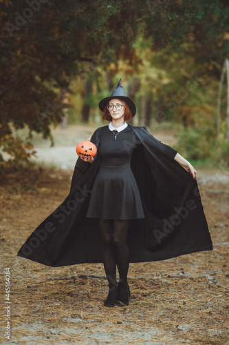 Obraz na płótnie Halloween witch. Portrait of a girl in a hat and a witch costume with a pumpkin in the forest. Ready for the holiday
