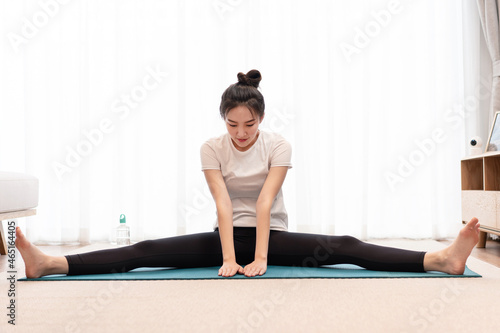 Productive activity concept a fit girl sitting on the mat open each leg to the opposite side looking concentrated on her exercise