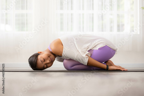 Asian woman working out in sportswear while doing yoga, seated in Child exercise, Balasana stance.