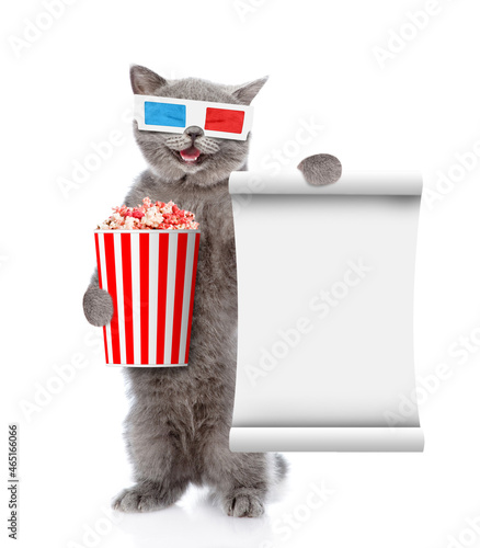Happy cat wearing 3d glasses holds basket of popcorn. isolated on white background