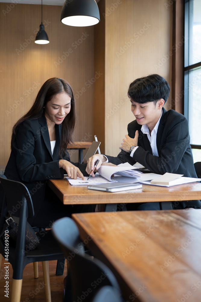 Two business colleagues sitting in office and reading paperwork together. Two business colleagues sitting in office and reading paperwork together.