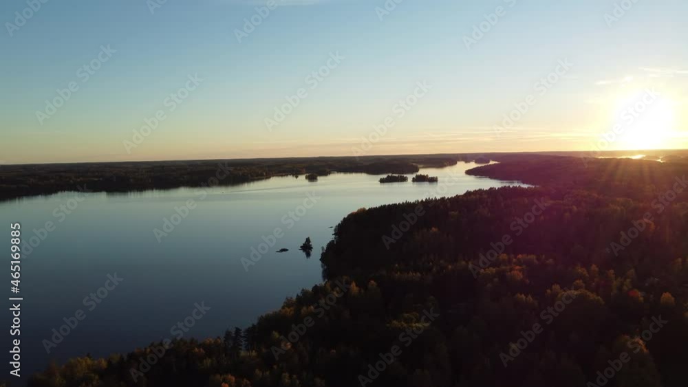 Cinematic drone shot of tranquil River surrounded by wild forest landscape during sunset lights and blue sky - Finland,Northern Europe Cinematic drone shot of tranquil River surrounded by wild forest landscape during sunset lights and blue sky - Finland,Northern Europe