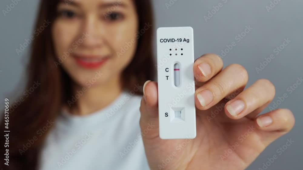 happy woman holding Coronavirus(Covid-19) negative test result with Antigen Rapid Test kit (ATK) happy woman holding Coronavirus(Covid-19) negative test result with Antigen Rapid Test kit (ATK)