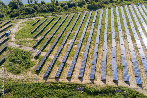 Aerial view of solar power plant on green field. Electric farm with panels for producing clean ecologic energy.