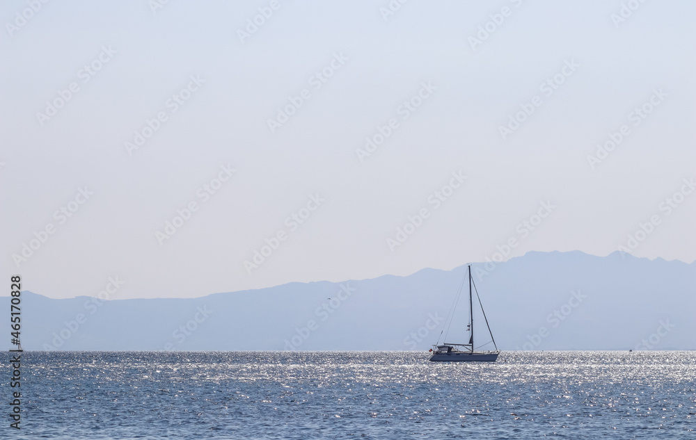 Blue sea waves sparkling in the sun and a yacht. Summer holidays concept
