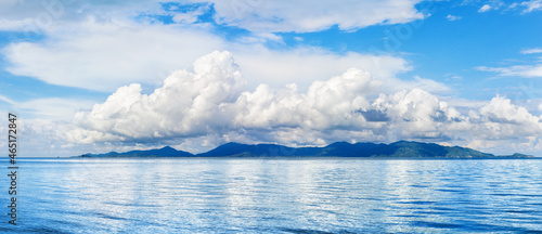 Koh Phangan wide panoramic view from Koh Samui, Thailand. Beautiful tropical island landscape, blue sea water waves, sunny sky, white cumulus clouds, summer holidays vacation travel, seascape panorama