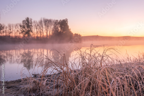 sunrise landscape with morning fog in the forest lake. bare trees reflected in the river water at morning fog. autumn scenic view of lake in foggy weather. cold fall colors. wanderlust