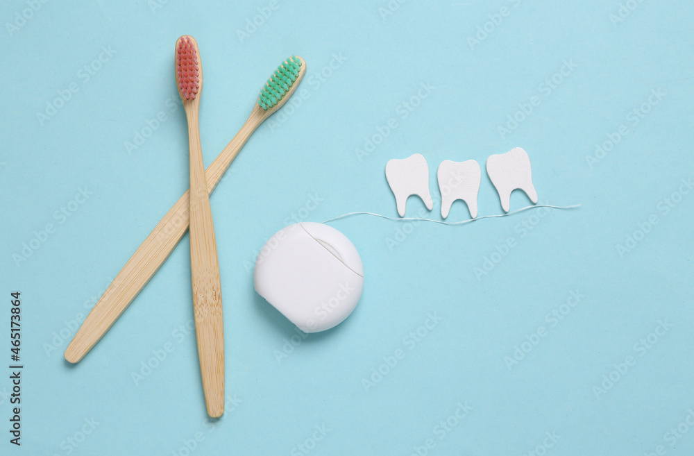 Dental care concept. Eco toothbrushes, dental floss with teeth on blue background. Top view. Flat lay Dental care concept. Eco toothbrushes, dental floss with teeth on blue background. Top view. Flat lay