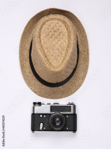 Straw hat and retro camera on white background. Top view