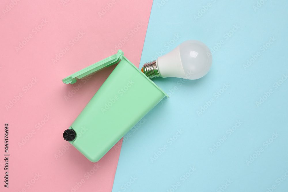Toy trash can with led light bulb on pink blue background. Recycling, eco concept. Top view, flat lay Toy trash can with led light bulb on pink blue background. Recycling, eco concept. Top view, flat lay