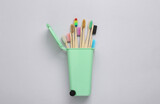 Toy trash can with eco wooden toothbrushes on gray background. Recycling, eco concept. Top view, flat lay