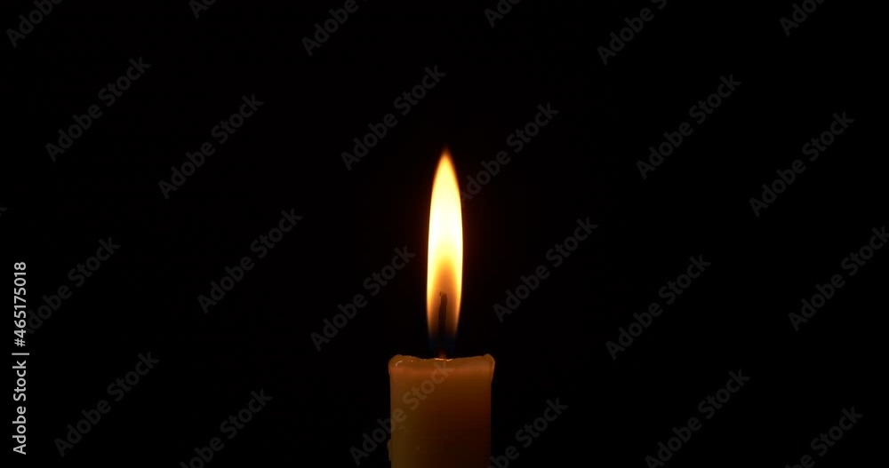 Close-up burning single candle flame isolated on black background, 4K video Close-up burning single candle flame isolated on black background, 4K video