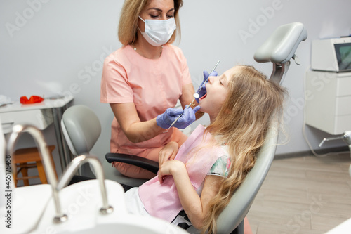 Sweet little girl in the dental chair. The dentist examines the teeth of the child's patient. Pediatric dentistry