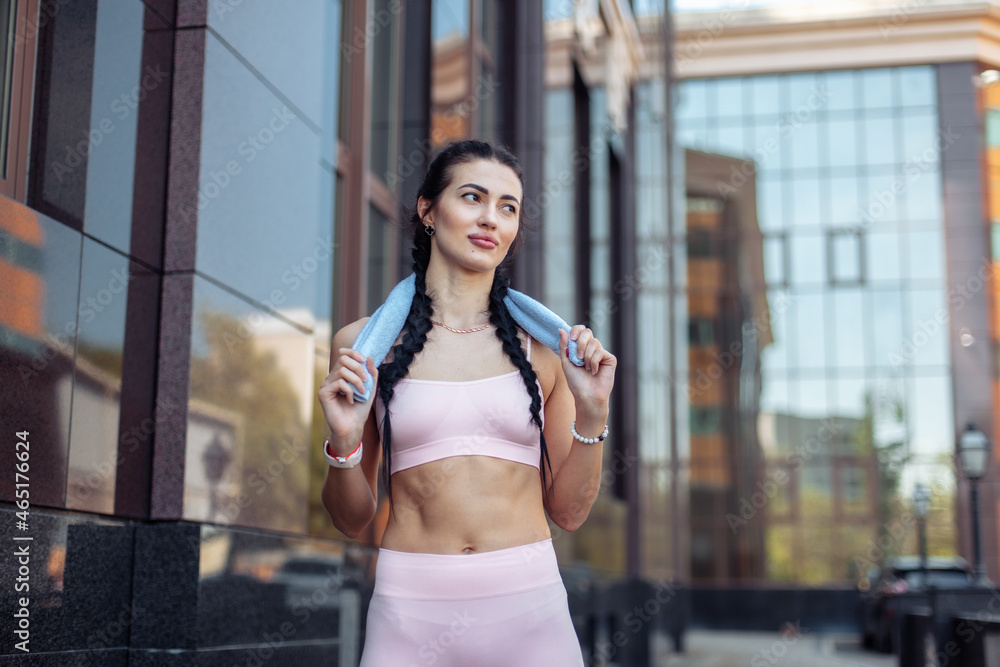 Young slim woman with towel on her shoulders in city Young slim woman with towel on her shoulders in city