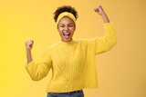 Active outgoing confident cheerful african-american female fan place bet hopefully yelling encourage team win standing raised fists victory celebrating gesture shouting proudly, yellow background
