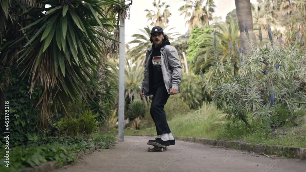 Young Skater skating in garden walkway with palmtrees, tracking shot Young Skater skating in garden walkway with palmtrees, tracking shot
