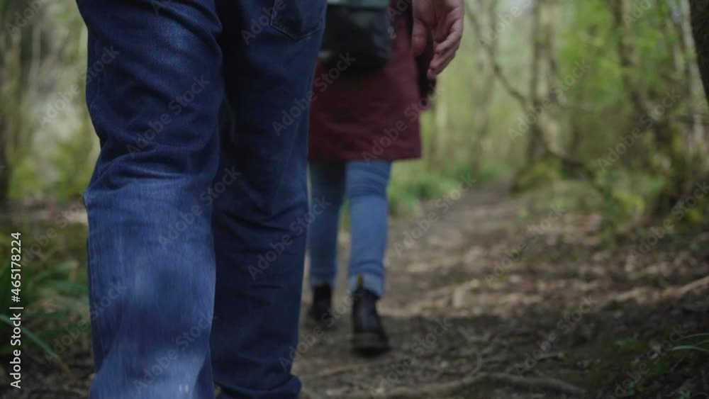 Dad carries toddler boy through forest, walks forest trail, feet angle Dad carries toddler boy through forest, walks forest trail, feet angle