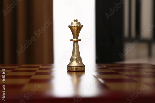 Golden Queen chess piece on board indoors photo