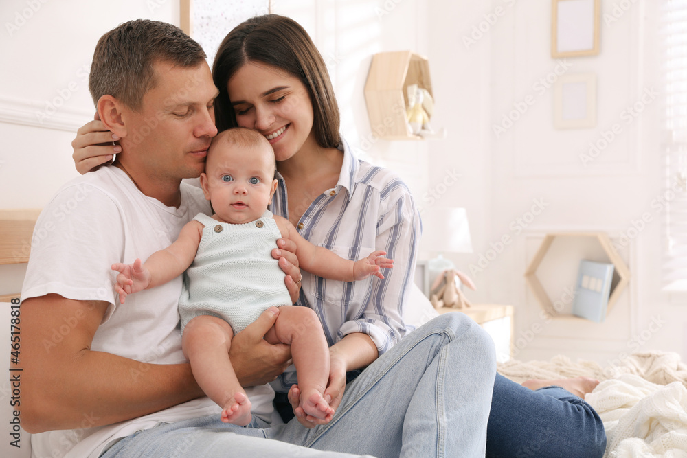 Happy family with their cute baby on bed at home