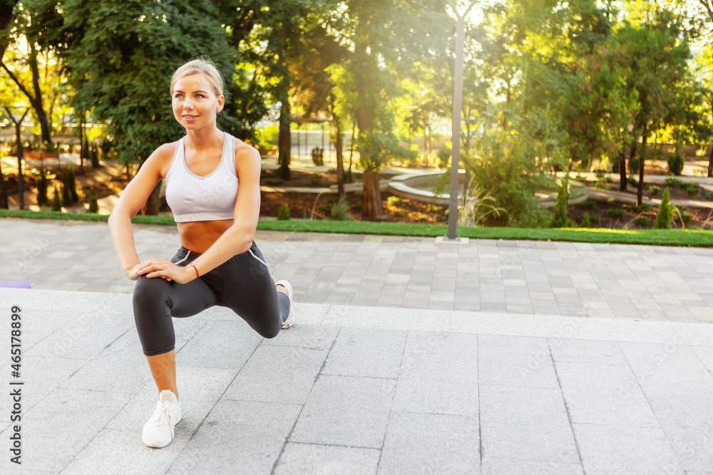Attractive young slim fitness woman dressed in sportswear doing stretching and warm-up exercises before training outdoors Attractive young slim fitness woman dressed in sportswear doing stretching and warm-up exercises before training outdoors