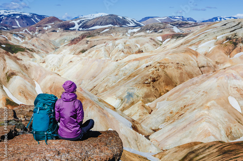 Woman hiker with backpack with view of volcanic mountains, hiking loop from viewpoint. Freedom, adventure.