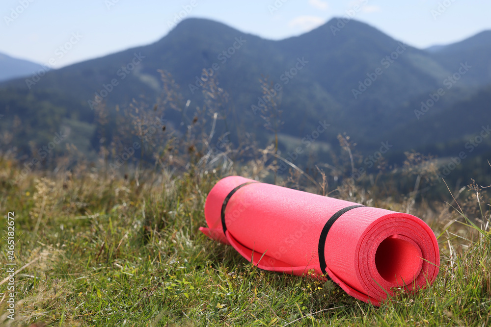 Rolled sleeping pad on grass in mountains, space for text Rolled sleeping pad on grass in mountains, space for text