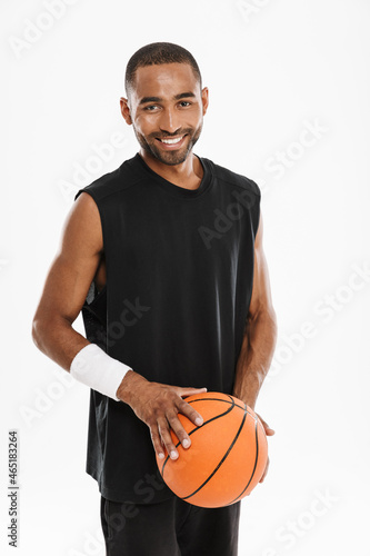 Young black sportsman smiling at camera while posing with basketball