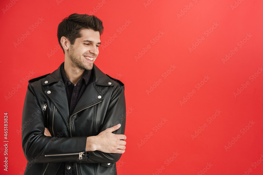 Young unshaven man wearing leather jacket smiling aside Young unshaven man wearing leather jacket smiling aside