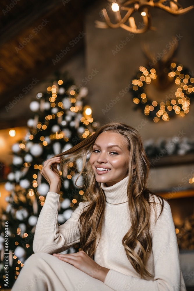 young beautiful woman model with long hair in a beige suit christmas tree christmas In brown wooden houses young beautiful woman model with long hair in a beige suit christmas tree christmas In brown wooden houses