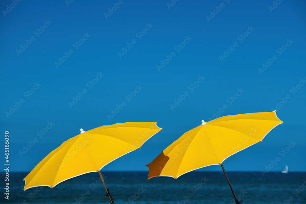 two yellow umbrellas and sea and blue sky