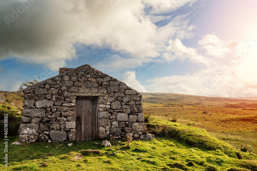 Old abandoned stone house without the roof. Sunset time. Rural Irish farm building. Dramatic sky. Old architecture example. Top quality frame . History and heritage concept. Connemara, Ireland photo