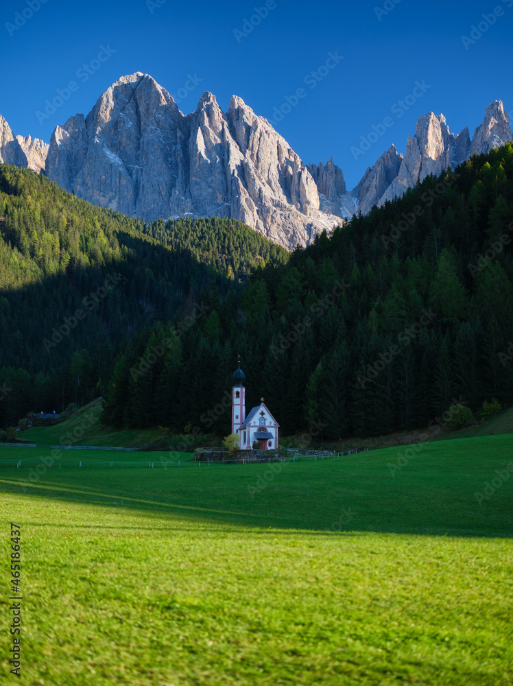Santa Maddalena. Val di Funes. Dolomite Alps. Italy. Church in the meadow. The mountains and the forest before sunset. Natural landscape in the summertime. Photo in high resolution..