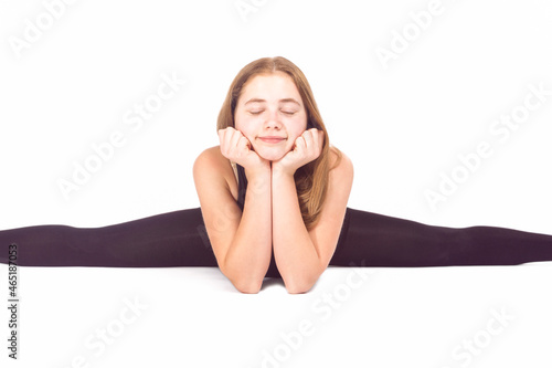 Young Caucasian Sportswoman Rhythmic Gymnast In Training Outfit During Line Split Stretching Exercises While Laying on Floor On White.